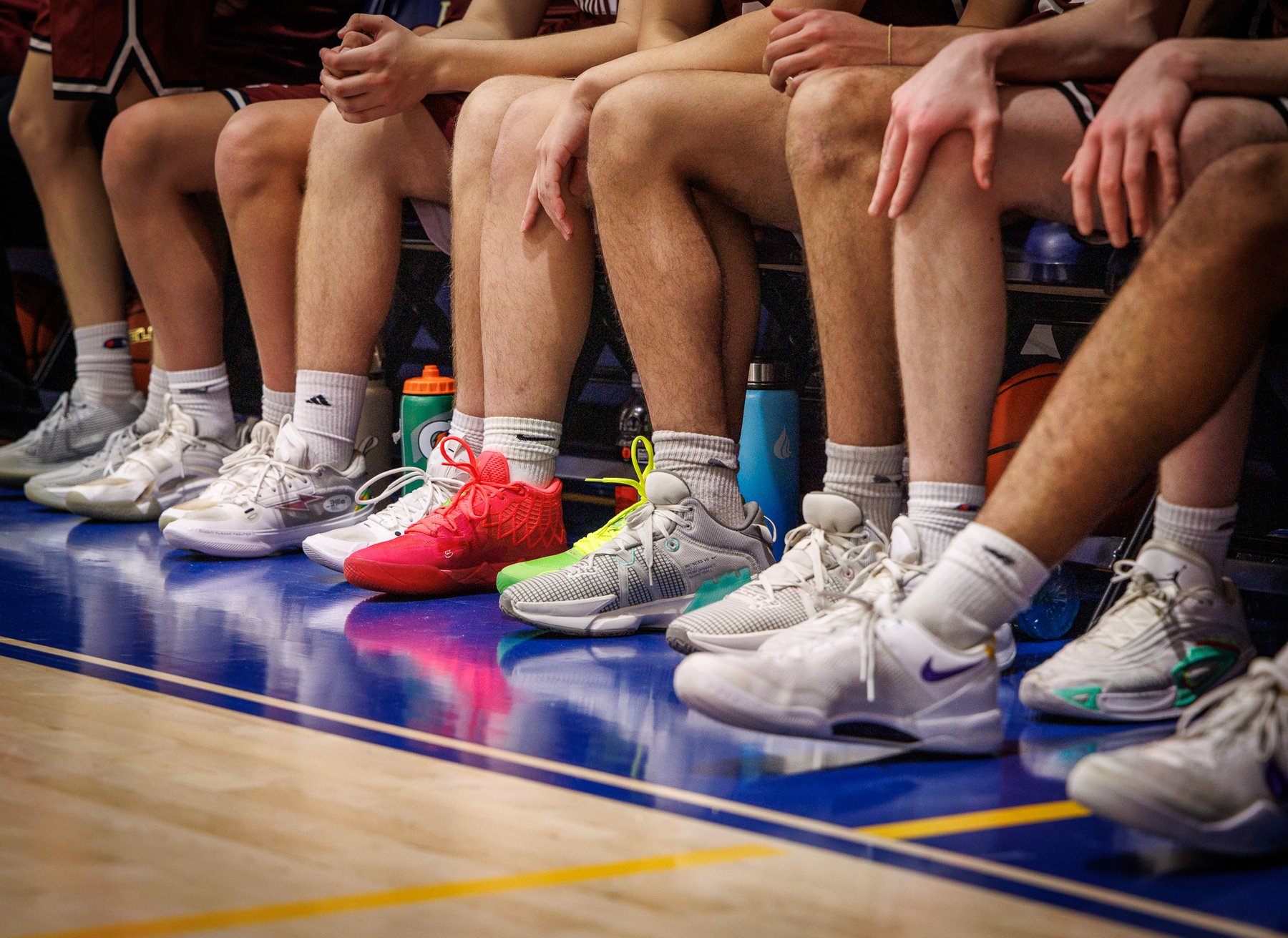 Row of colorful basketball sneakers on the bench during a high school game
