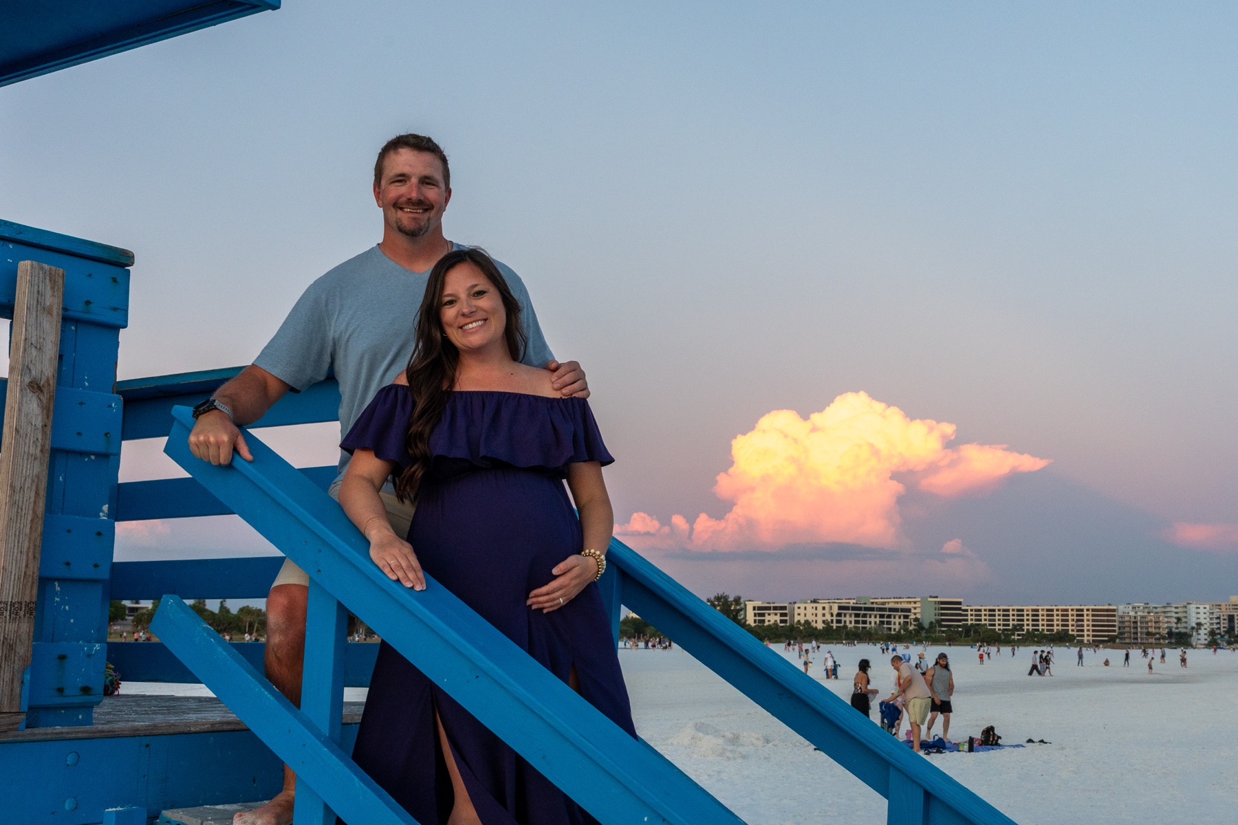Couple posing on blue stairs with a sunset-lit cloud in the background