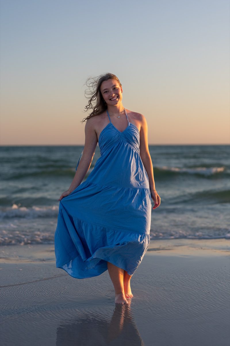 Young woman in a blue dress standing on the beach at golden hour